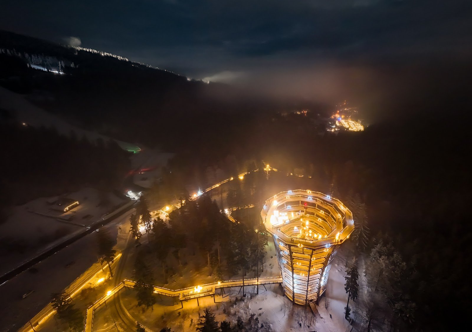 Osvijetljena turistička staza u prirodi i svjetlosni park tijekom noći pod snijegom.